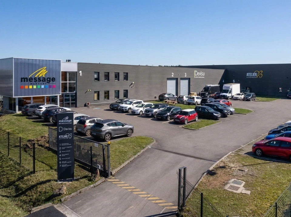 Atelier industriel avec une rangée de machines à broder professionnelles **Barudan** multi-têtes alignées